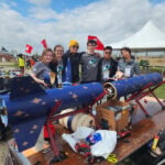 MIT First Nations Launch team stands in back of their rocket.