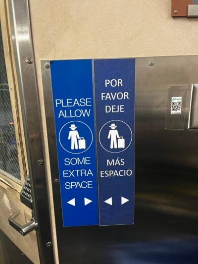 sign on a wall that directs people in an airport to make space between themselves and other people