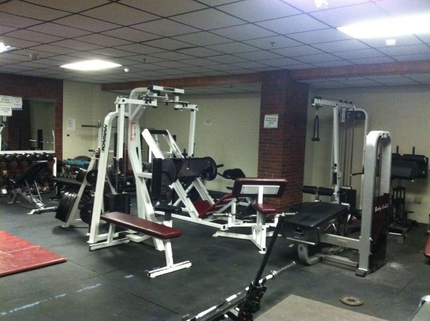 a low-res photo of a gym with some machines and fluorescent overhead lighting