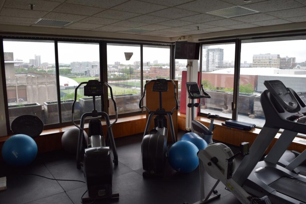 a picture of a dimly lit corner of a gym with several stationary biking machines