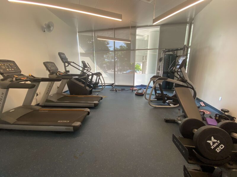 a picture of a mid-sized gym with a couple cardio machines and some free weights