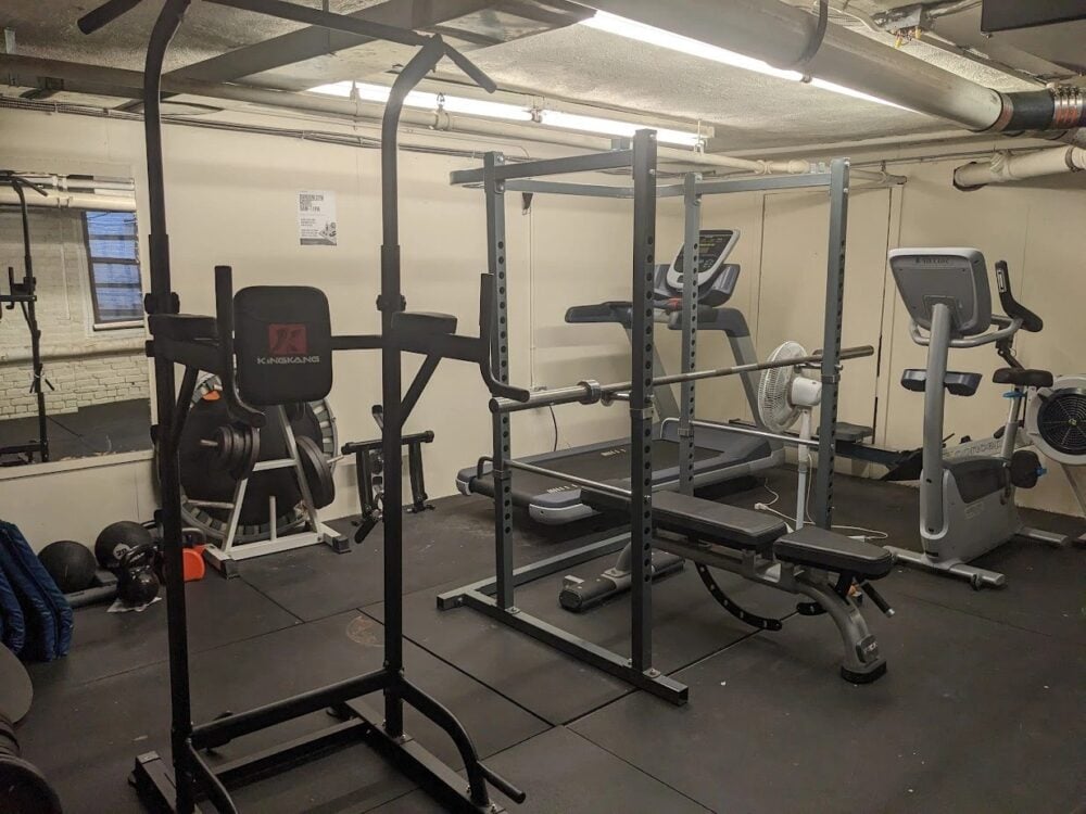 a picture of a dark and grungy gym with a rack and a couple machines