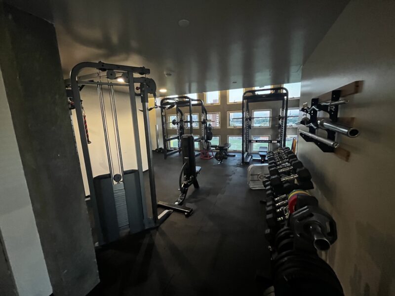 a picture of a dark gym with many windows and some free weights and machines