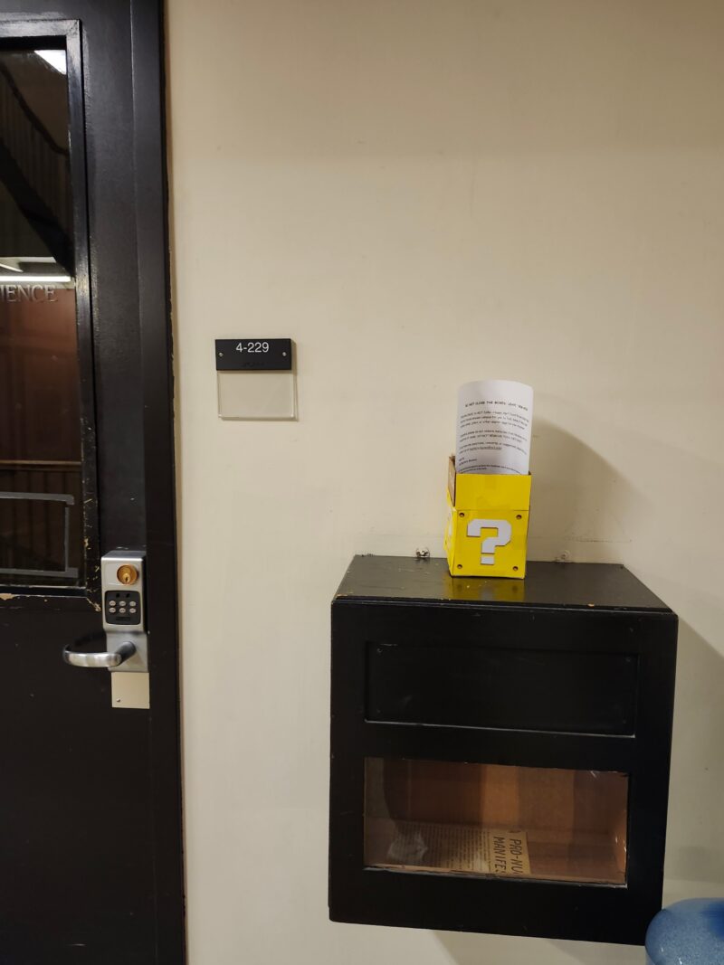 Small yellow box w/ question mark sitting outside a door
