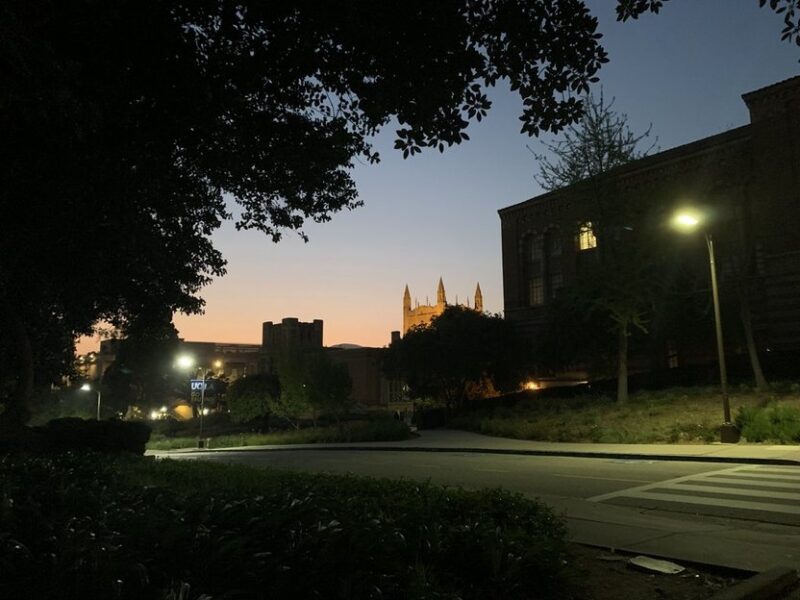 a castle-like structure stands tall, far behind other buildings obscured by shadow.