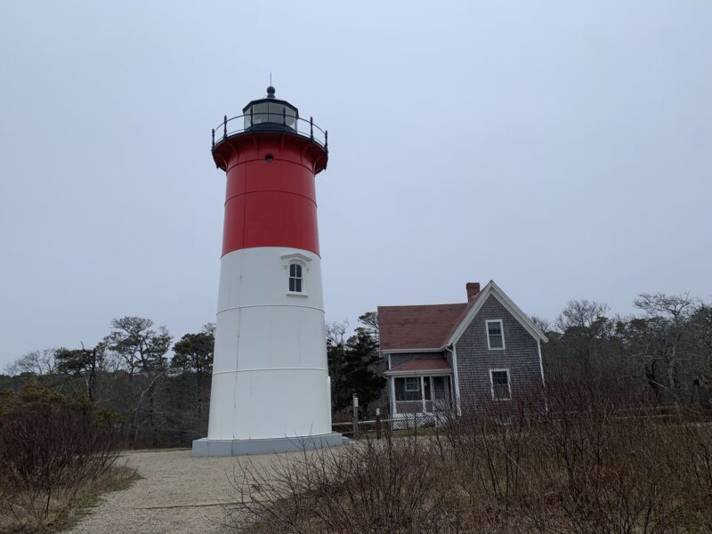 a lighthouse and a house in cloudy weather