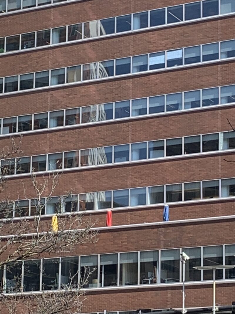 a brick building with three umbrellas, yellow, red, and blue