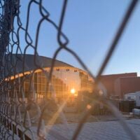 The reflection of the sun against a Kresge window seen through a chain-link fence