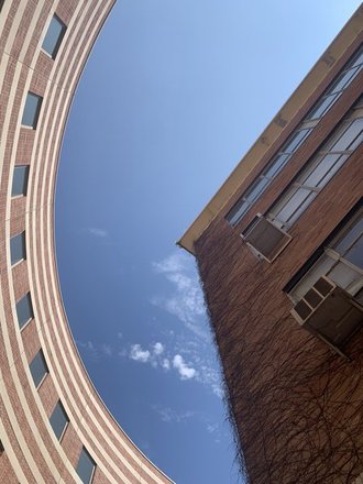 two buildings, looking up on them. one curves, making an arch around the corner of a more standard shaped building