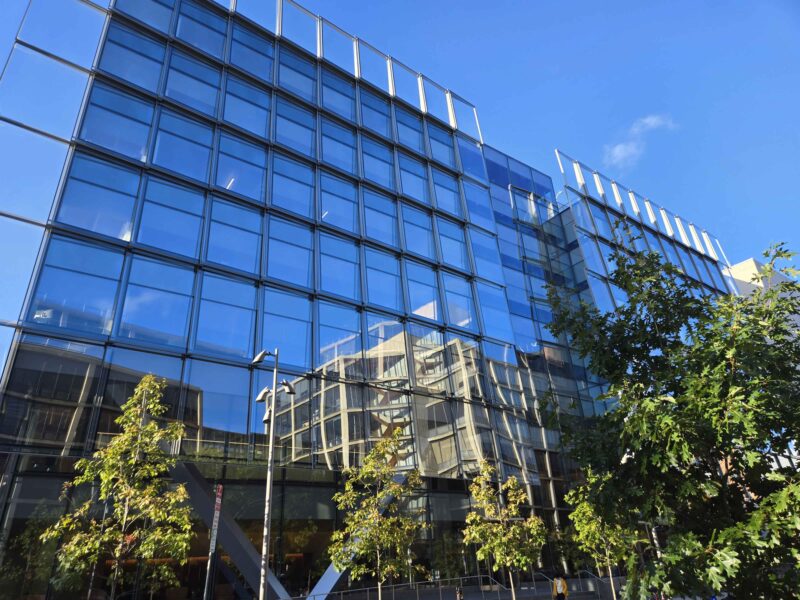 A glass building front reflects the sky