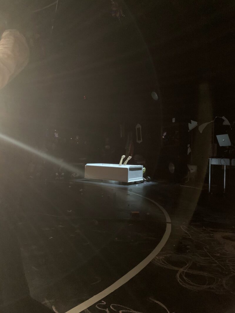 a bathtub-like structure in an otherwise dark room, with two hands reaching out.
