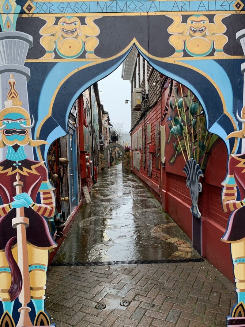 a street with red and black houses seen through a fancy gate, painted to look like cartoon soldiers on either side