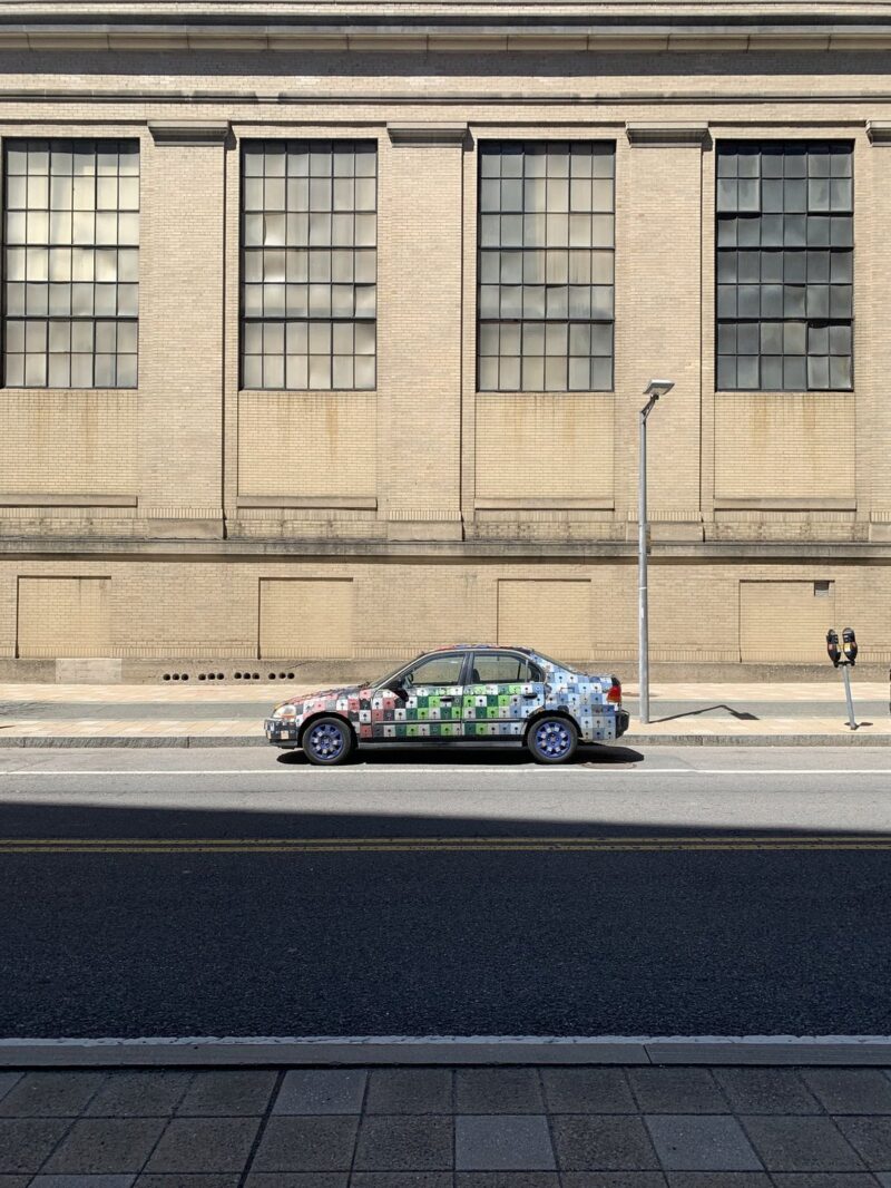 a multicolored car against the beige mit wall