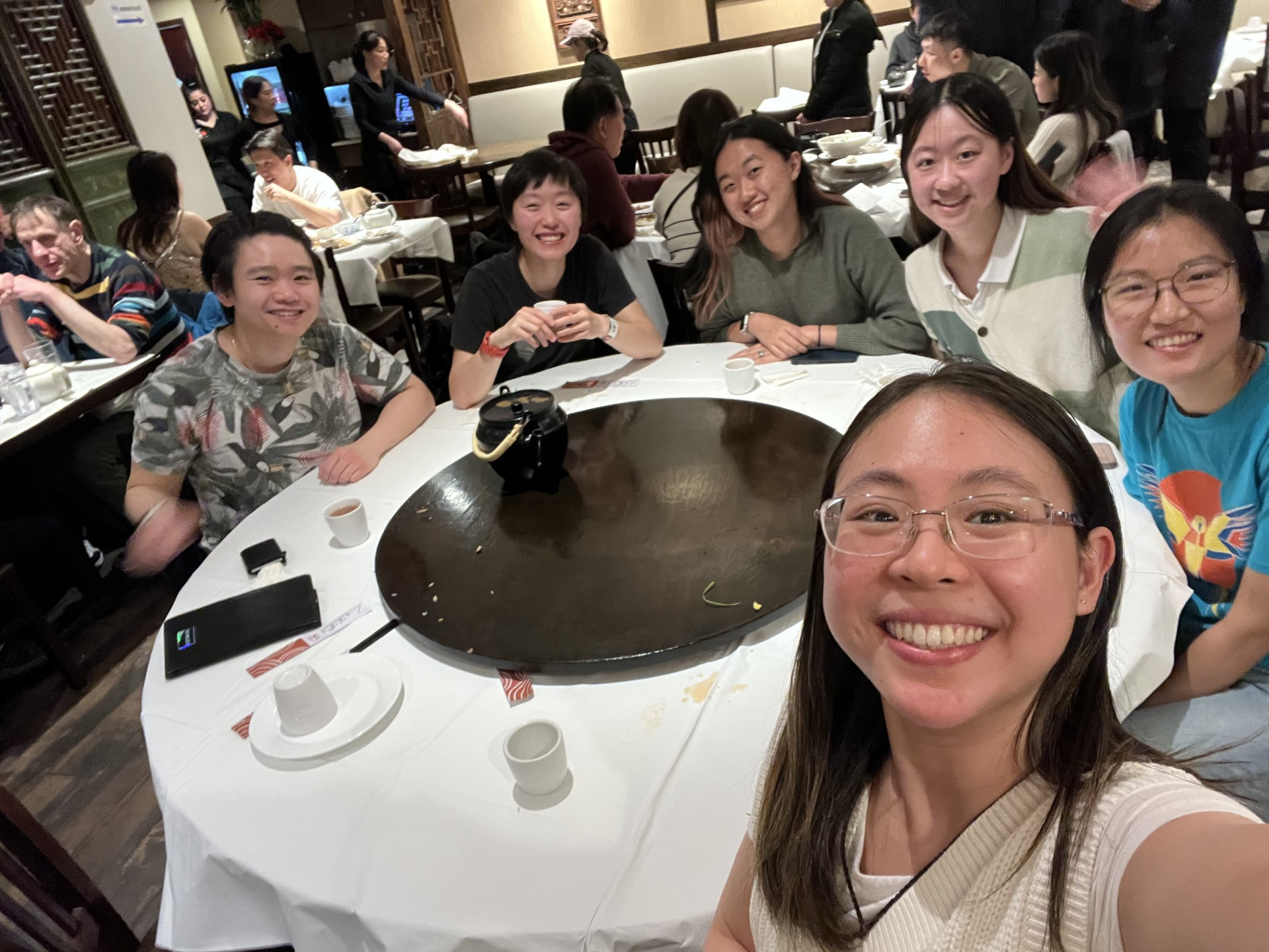 A group of six people around a circular dinner table. 