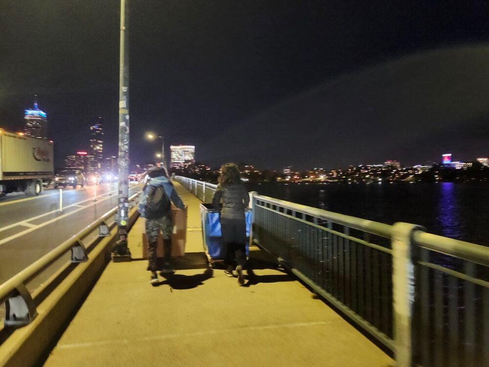 two people pushing carts across a bridge