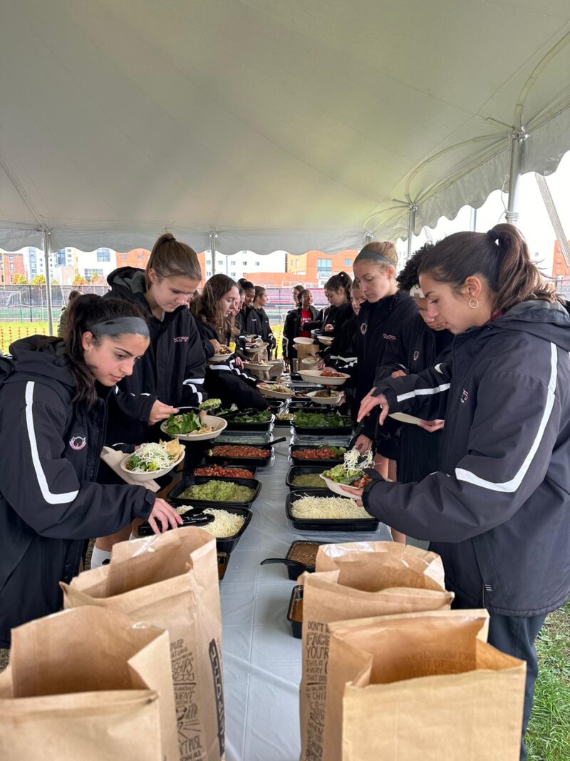 Team gathered around chipotle buffet table.