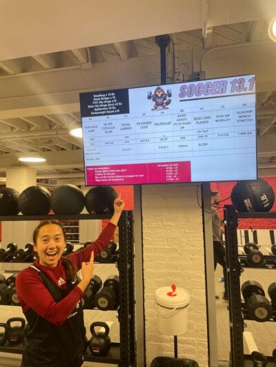 Player pointing at a TV with a workout on it.