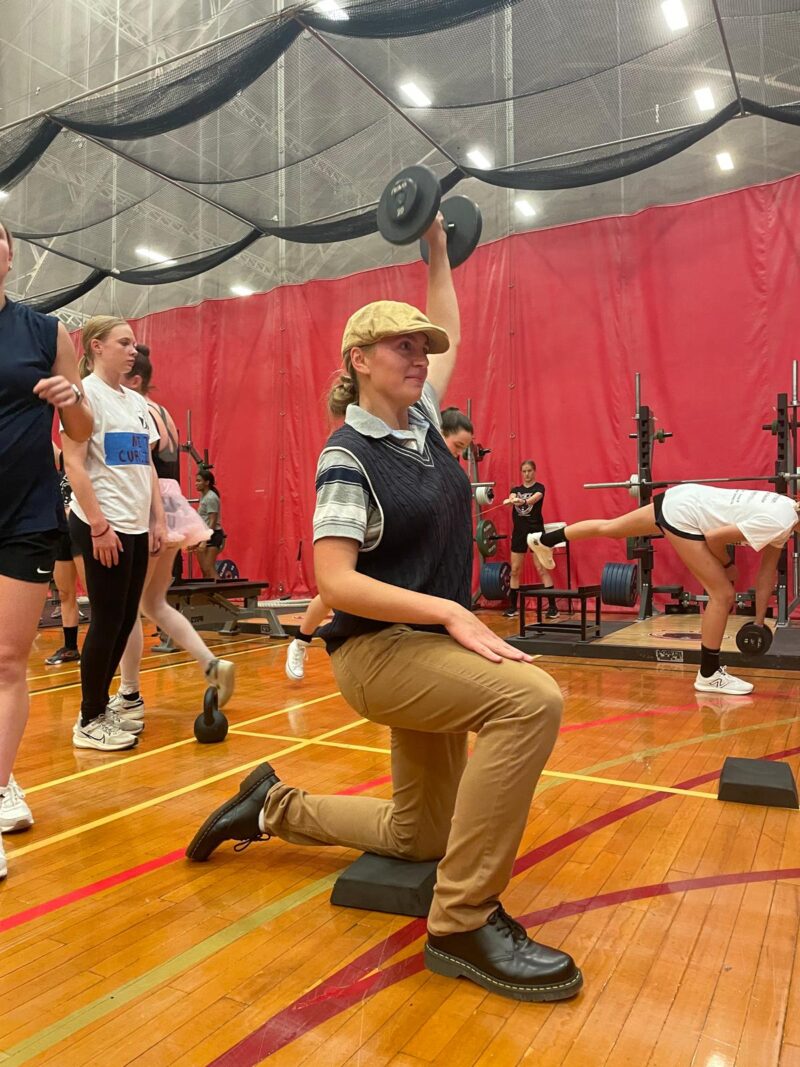 Soccer player dressed as golfer lifting a weight.