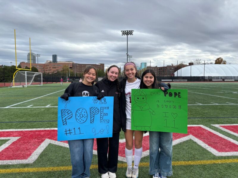 Girls posing with signs for soccer senior day.