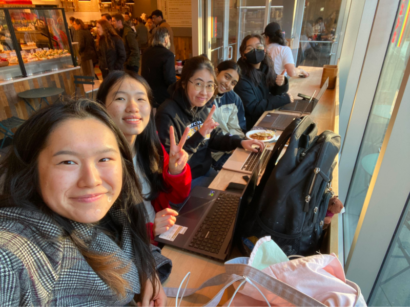 a selfie w 5 people sitting at a cafe bench