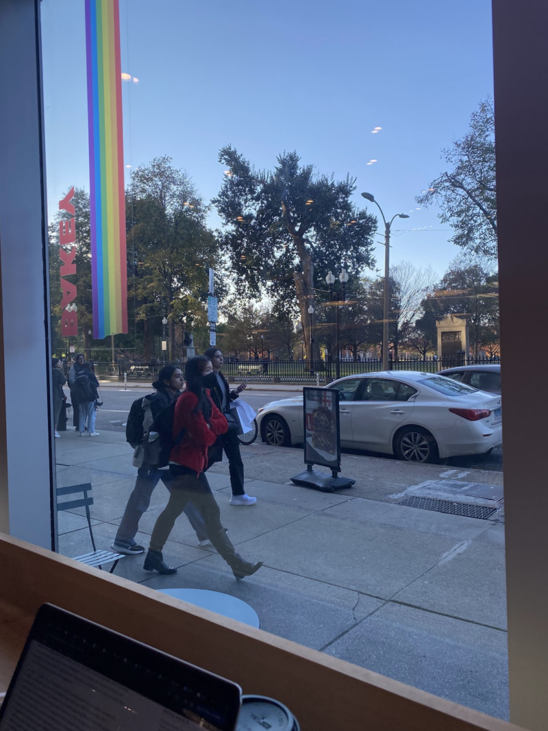 two people walking away from a shop, taking through the window of the shop