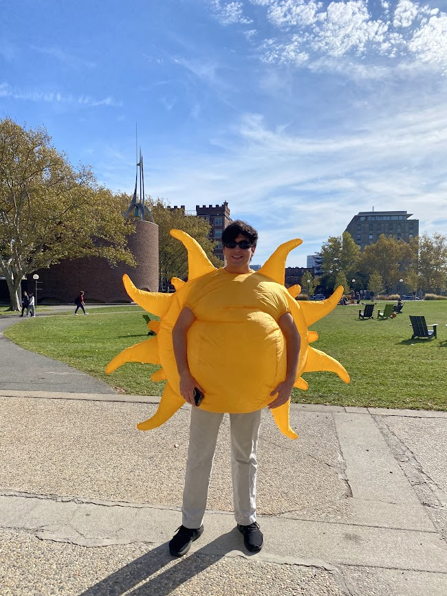 person standing in an inflatable sun costume and wearing sunglasses
