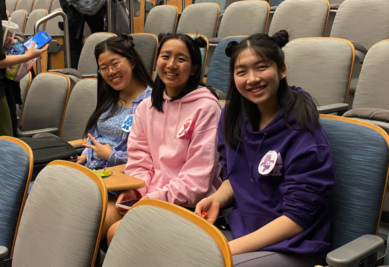 three people sitting in a row dressed like care bears