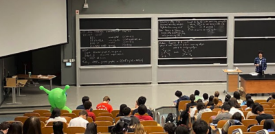 photo of lecture hall with a notable green inflatable alien sitting up front