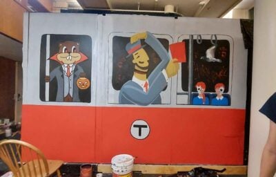 a painted wall that depicts a red line train with vampire tim, evil charlie, and two zombie twins looking out of the window