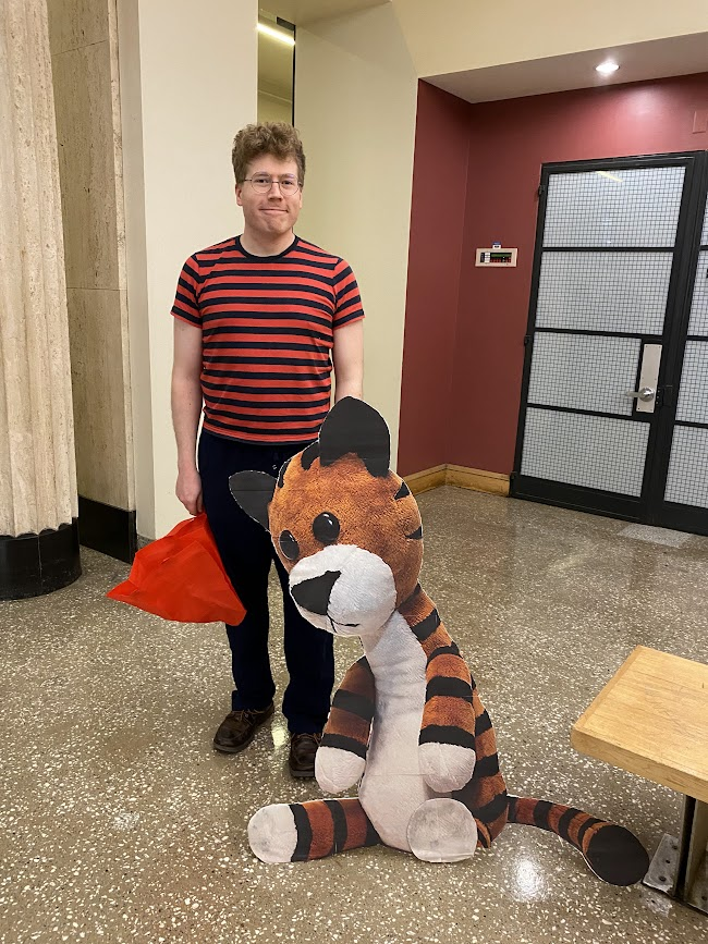 person dressed like calvin with a cardboard printout of a life-sized hobbes