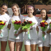 Soccer seniors smiling with flowers.