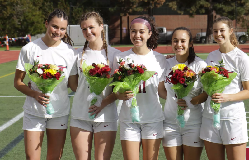 Soccer seniors smiling with flowers.