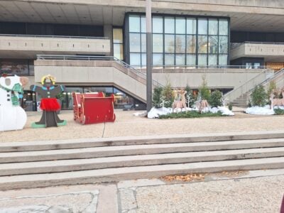 A Christmas decor setup outside of the student center. There are two character cutouts, a sleigh, and a reindeer setup.