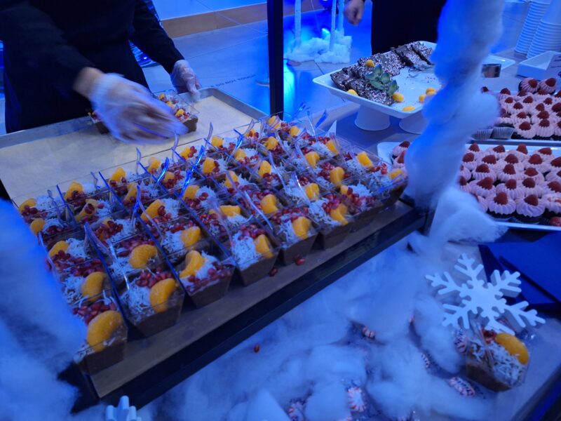 A display of chocolate puddings on a long white table with Christmas decorations