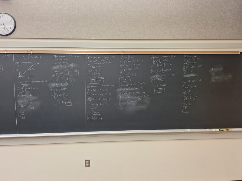 A wall-length blackboard with practice problems for multivariable calculus.