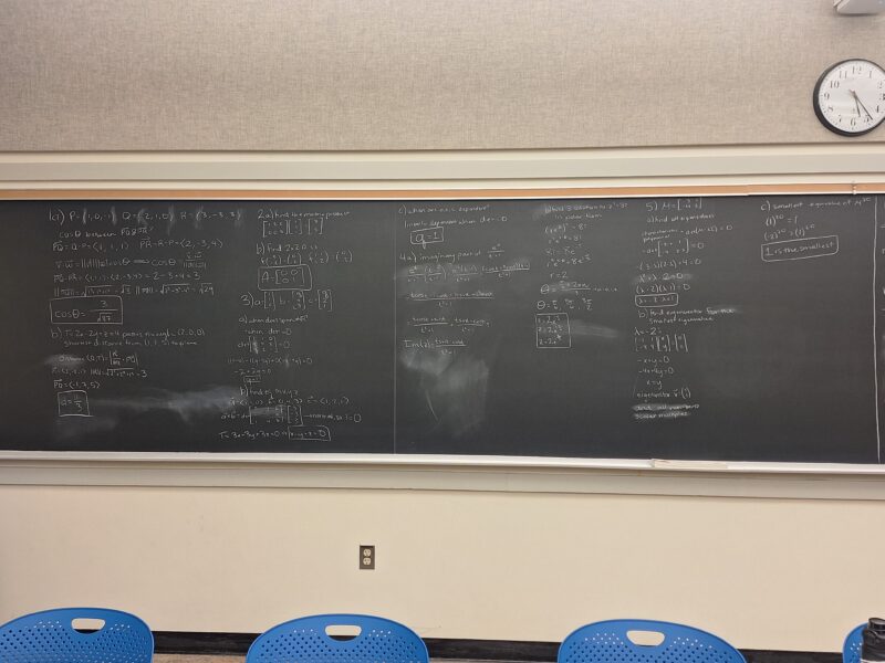 A wall-length blackboard with practice problems for multivariable calculus.
