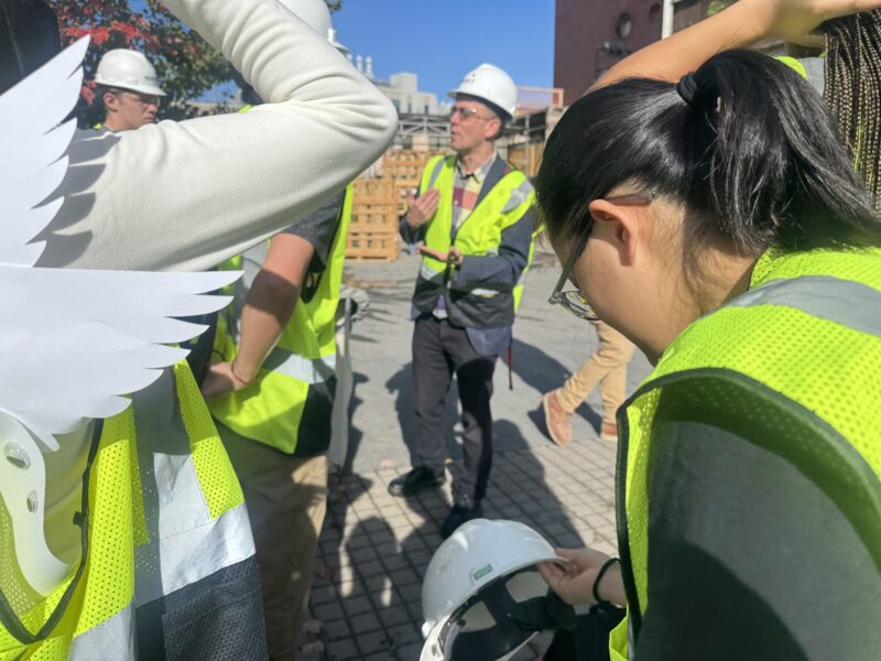 Photo of students in a circle wearing hardhats getting ready to tour the Metropolitan Warehouse Building.
