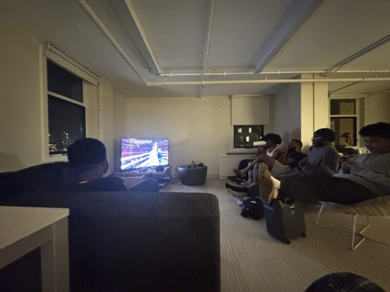 Photo of student lounge with students seated in couches watching the Jake Paul and Mike Tyson fight.