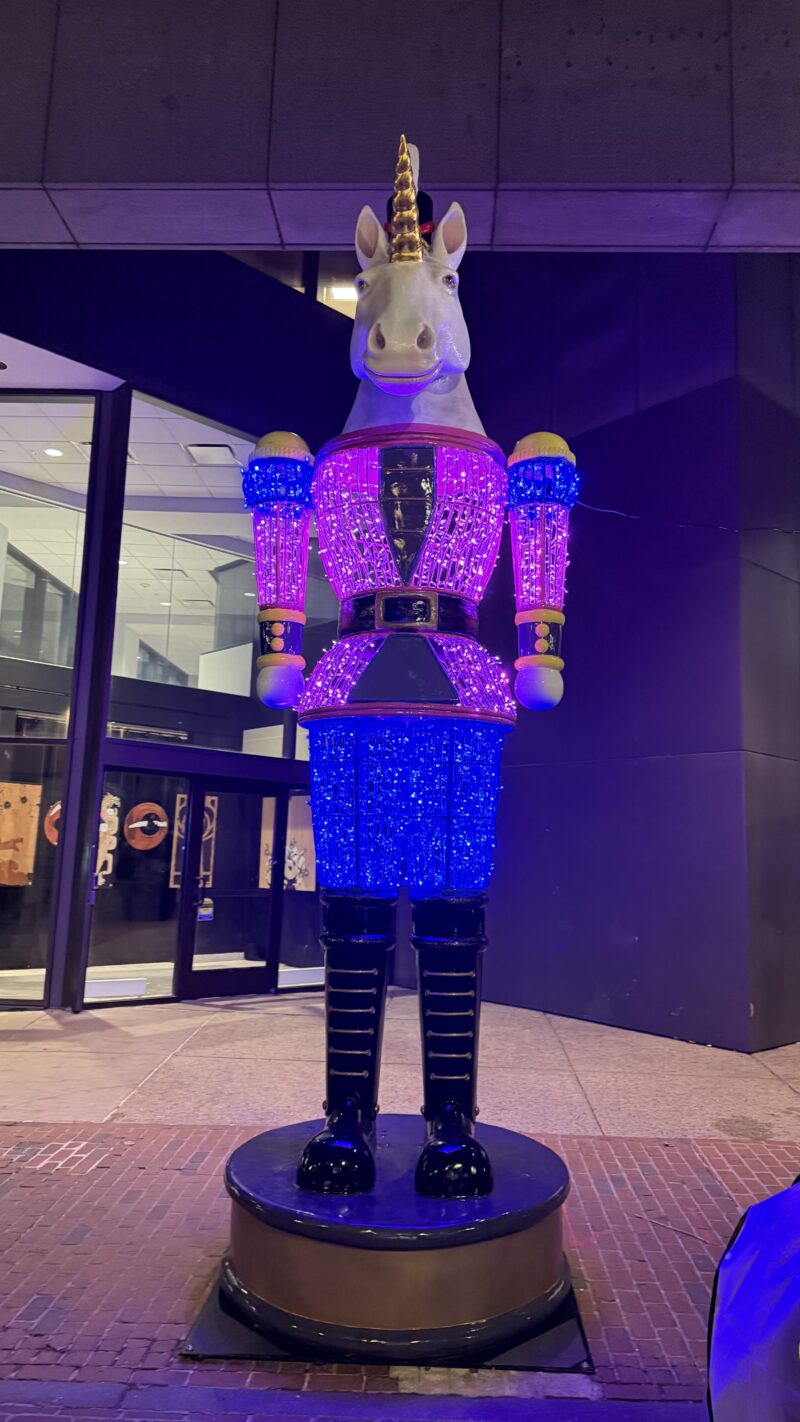A unicorn statue dressed in a pink and purple prince outfit.