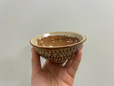 a small brown bowl with grooves in the side