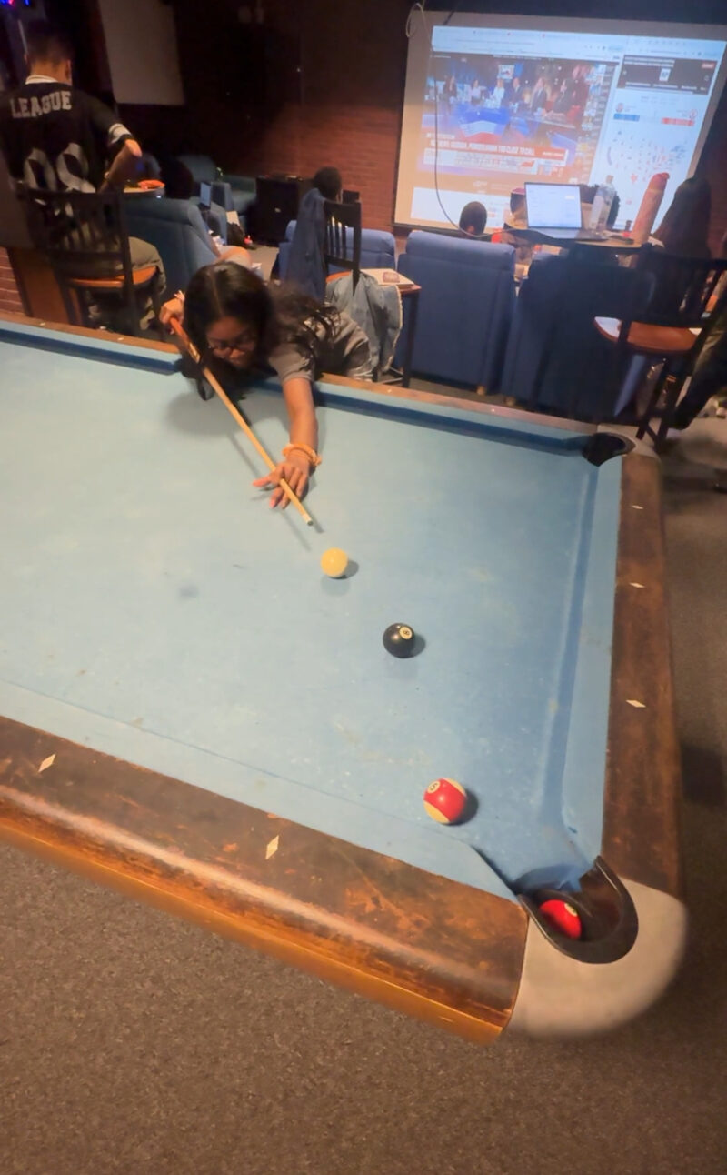 Picture of student leaning over pool table to make a shot.