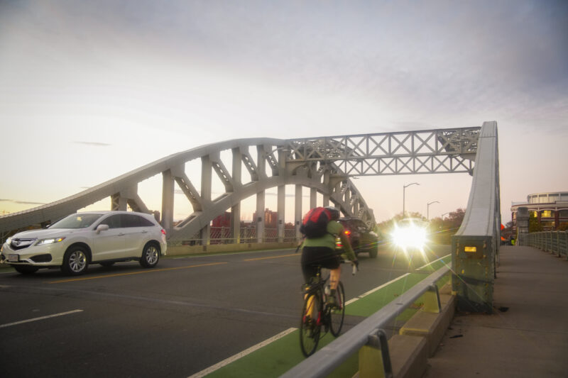 Photo of the Boston University Bridge with biker and cars crossing.