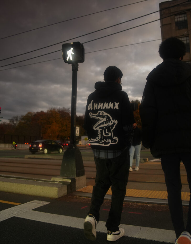 Photo of two students crossing the road with a walk sign visible in the background.