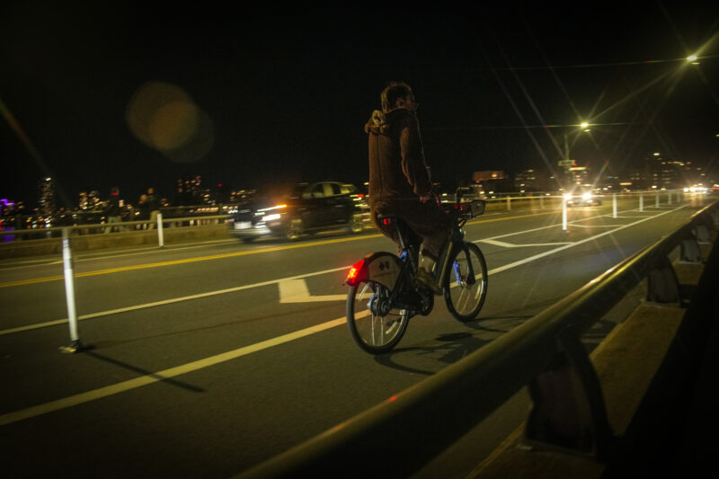Photo of a biker in a bear suit riding across the Harvard Bridge.
