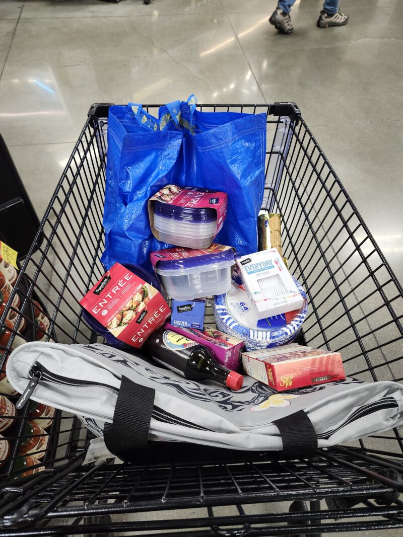Shopping cart filled with bags, tupperware, shoyu, plates, etc.