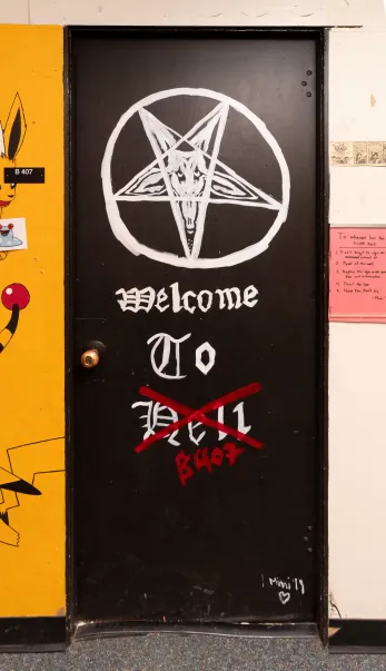 black door with white text and a pentagram. The text says "welcome to hell" but hell is crossed out and replaced with B407