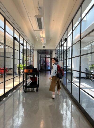 a woman walking with a backpack in a hallway with glass walls