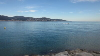 A view of the town Roses from across a blue Gulf. A single boat is in the distance. 