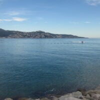 A view of the town Roses from across a blue Gulf. A single boat is…