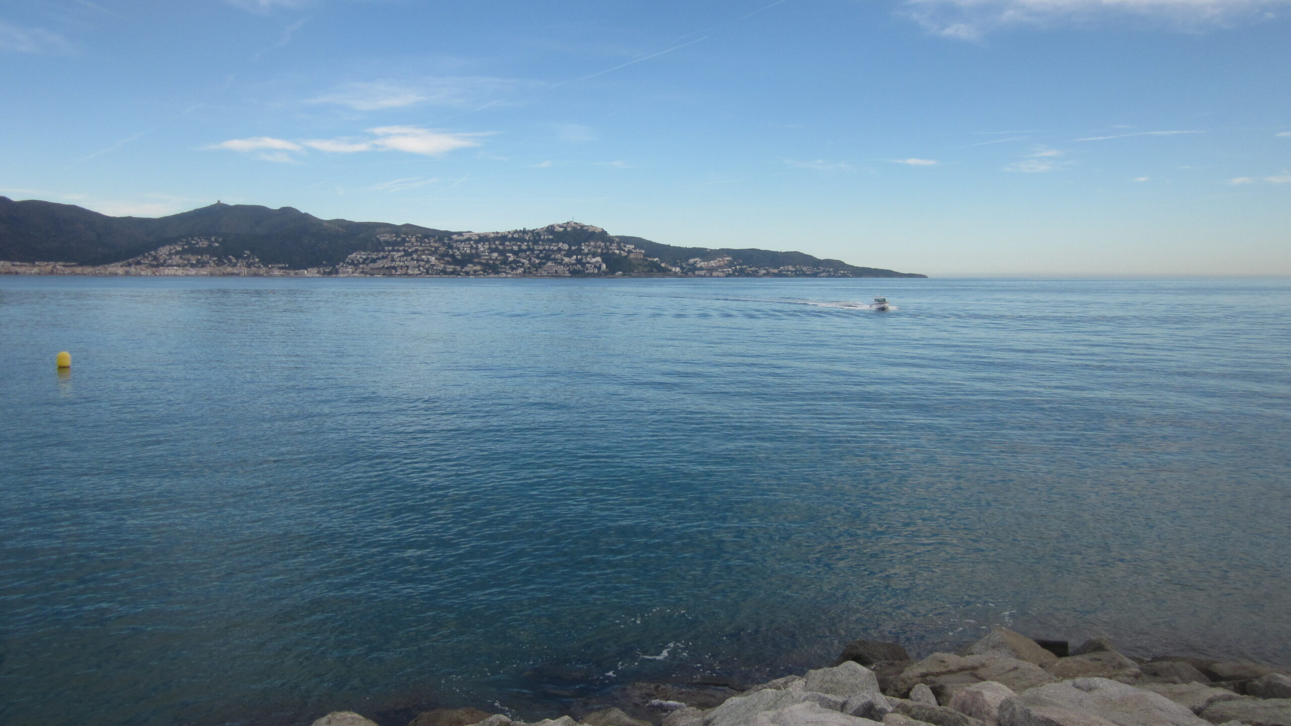 A view of the town Roses from across a blue Gulf. A single boat is&hellip;